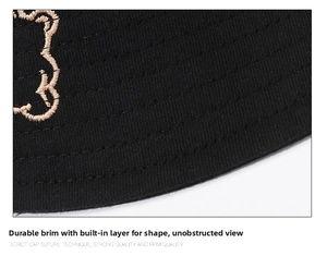 Detailed macro view of black cotton bucket hat brim with reinforced stitching and embroidery