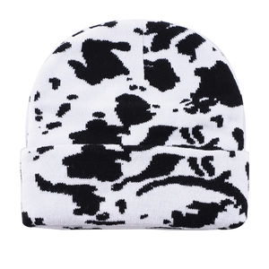 Winter knit beanie with black and white cow print pattern in a classic cuff style