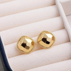 Detailed view of square gold earrings with hammered metal texture and twisted rope edges
