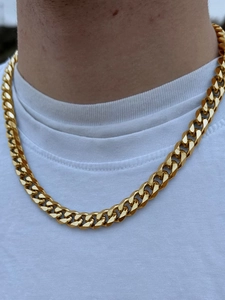 Detail shot of the golden stainless steel Cuban link necklace worn on a model's neck