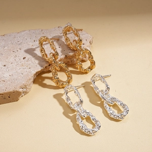 Boucles d'oreilles ovales plissées en or et argent posées sur un support en pierre