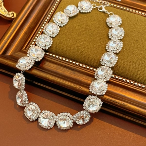 Detailed view of silver necklace with round crystals set on brown leather and golden frame