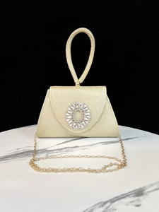 Makroaufnahme der goldenen Glitzer-Abendtasche mit Kristallschließe und Metallkette