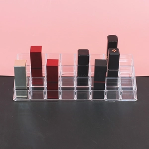 Macro detail of a 24-slot clear acrylic lipstick organizer on a pink and black background