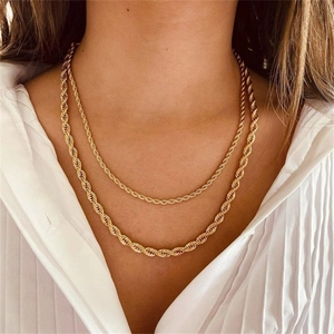 Close-up of a double-layered gold twisted rope chain necklace on a model wearing a white shirt