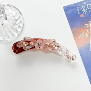Detail of reddish-brown banana clip with pink bow and sparkling rhinestones