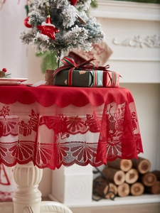 Detail of red Christmas tablecloth featuring white lace deer and snowflake patterns