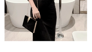 Close-up of black velvet evening clutch with gold leaf clasp held against a bathroom setting