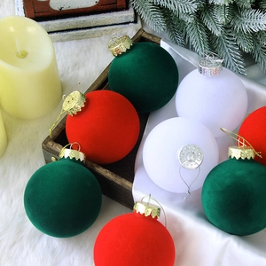Red, green, and white flocked Christmas ball ornaments in a rustic wooden tray setting