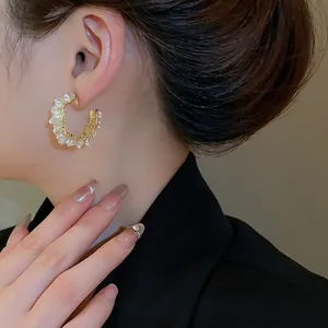 Vintage gold C-shaped earrings with crystal stones worn by a model in a side view