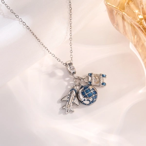 Close-up of travel charm necklace with silver airplane, globe, and suitcase pendants