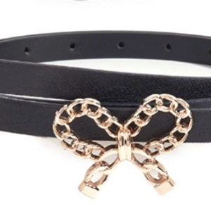 Elegant thin black belt with a gold-tone chain bow buckle on a clean white background