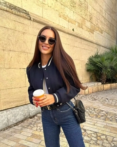Dettaglio ravvicinato della giacca bomber blu navy con finiture a righe e bottoni bianchi