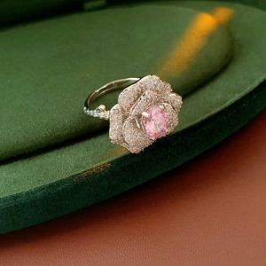 Detail of silver rose ring with pink oval gemstone and sparkling zircon petals on velvet