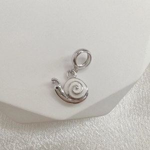 Macro view of a silver snail charm with white enamel and spiral detail for bracelets