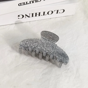 Close-up of a sparkling silver glitter hair claw clip on a minimalist white backdrop