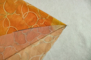 Detailed view of the orange geometric print fabric showing texture and stitching finish