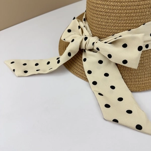Detail of wide-brim straw hat with elegant polka dot ribbon and oversized bow design