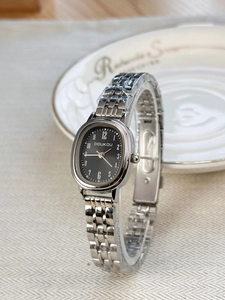 Close-up of women's quartz watch with oval black dial and silver stainless steel strap