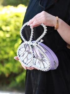 Detailed close-up of a purple butterfly-shaped clutch with sparkling rhinestone edges