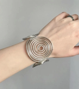 Macro view of wide silver metal bracelet with a minimalist concentric spiral design