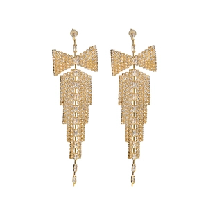Close-up of golden tassel earrings with bow design and sparkling rhinestone crystals