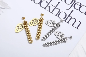 Close-up of gold and silver skull drop earrings with chunky Cuban chain links