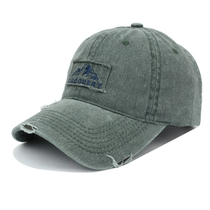 Close-up of olive green washed cotton baseball cap with mountain patch and distressed details