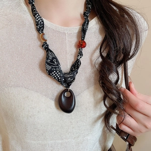 Close-up of ethnic fabric necklace featuring wooden oval pendant and mixed beads