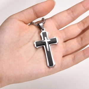 Detail of hand-held layered silver and black cross pendant with round bead chain