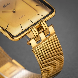 Macro shot of gold square quartz watch head and milanese mesh strap texture detail
