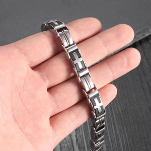 Men's stainless steel cross link bracelet with black silicone accents on dark background