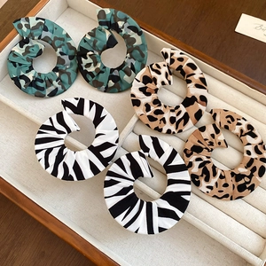 Detail showing fabric-wrapped spiral hoop earrings in camo, leopard, and zebra prints