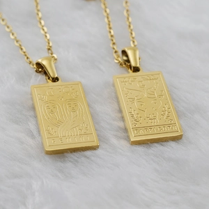 Detail of 18K gold-plated zodiac square pendants on white fur with Gemini and Capricorn designs
