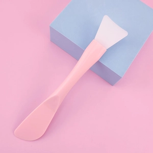 Detailed macro view of a pink silicone facial mask brush with plastic handle for DIY beauty