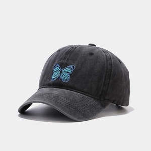 Detailed close-up of a blue butterfly embroidery on a vintage washed grey cotton baseball cap