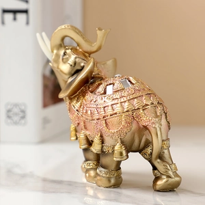 Golden elephant figurine with bell ornaments and ornate mirror details on marble surface
