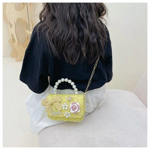 Detail of yellow tweed crossbody bag with pearl handle and metal chain on model