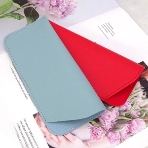 Detail of blue and red lychee grain leather sunglasses pouches on magazine with flowers