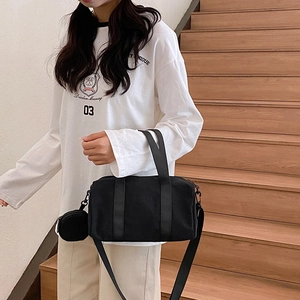 Minimalist black nylon Boston handbag with adjustable strap and small round pouch charm