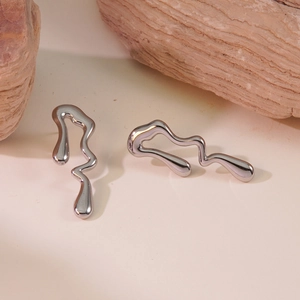 Macro detail of silver liquid metal lava earrings on textured natural stone base