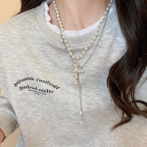 Détail d'un collier double rang avec pendentif croix argenté et perles sur mannequin