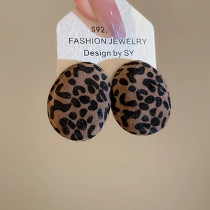Macro detail of oval leopard print flocked earrings with S925 silver needle on display card