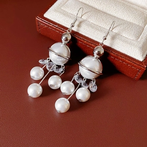 Detail of silver Saturn-shaped earrings with faux pearls and long crystal tassels