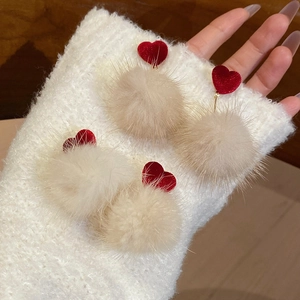 Gros plan de pompons beiges et de breloques en forme de cœur rouge sur des boucles