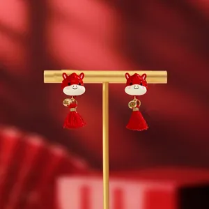 Detailed macro view of red pony earrings with golden coins and elegant red silk tassels