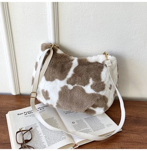Detail view of plush cow print tote bag with white leather strap and gold hardware accents