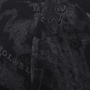 Vue macro du tissu noir avec motif graphique gris et détail d'oeillet brodé sur le chapeau
