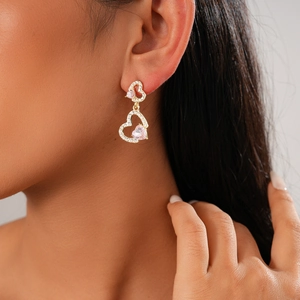 Detail of gold double heart earrings with pink gemstones and sparkling zircon pavé