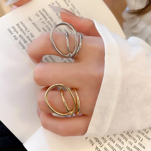Detail view of gold and silver layered geometric open rings on hand in a minimalist setting